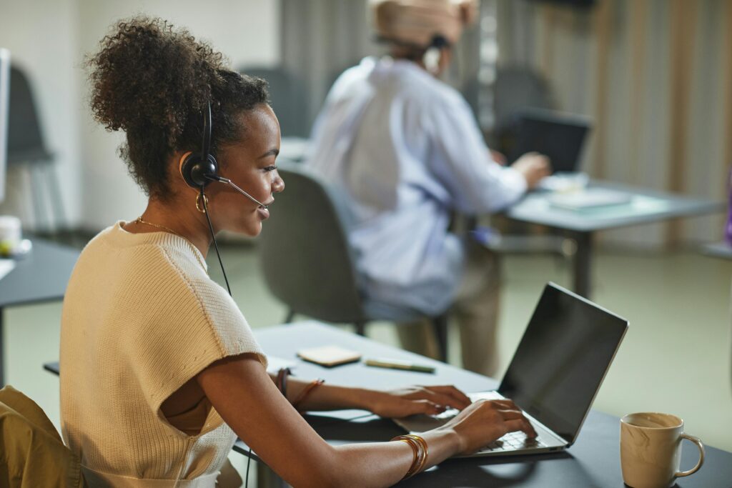 Focused African American woman working on a laptop in a modern office environment.